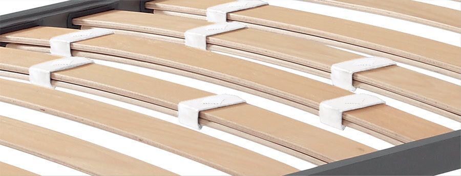 Slatted bed base with stiffness regulators